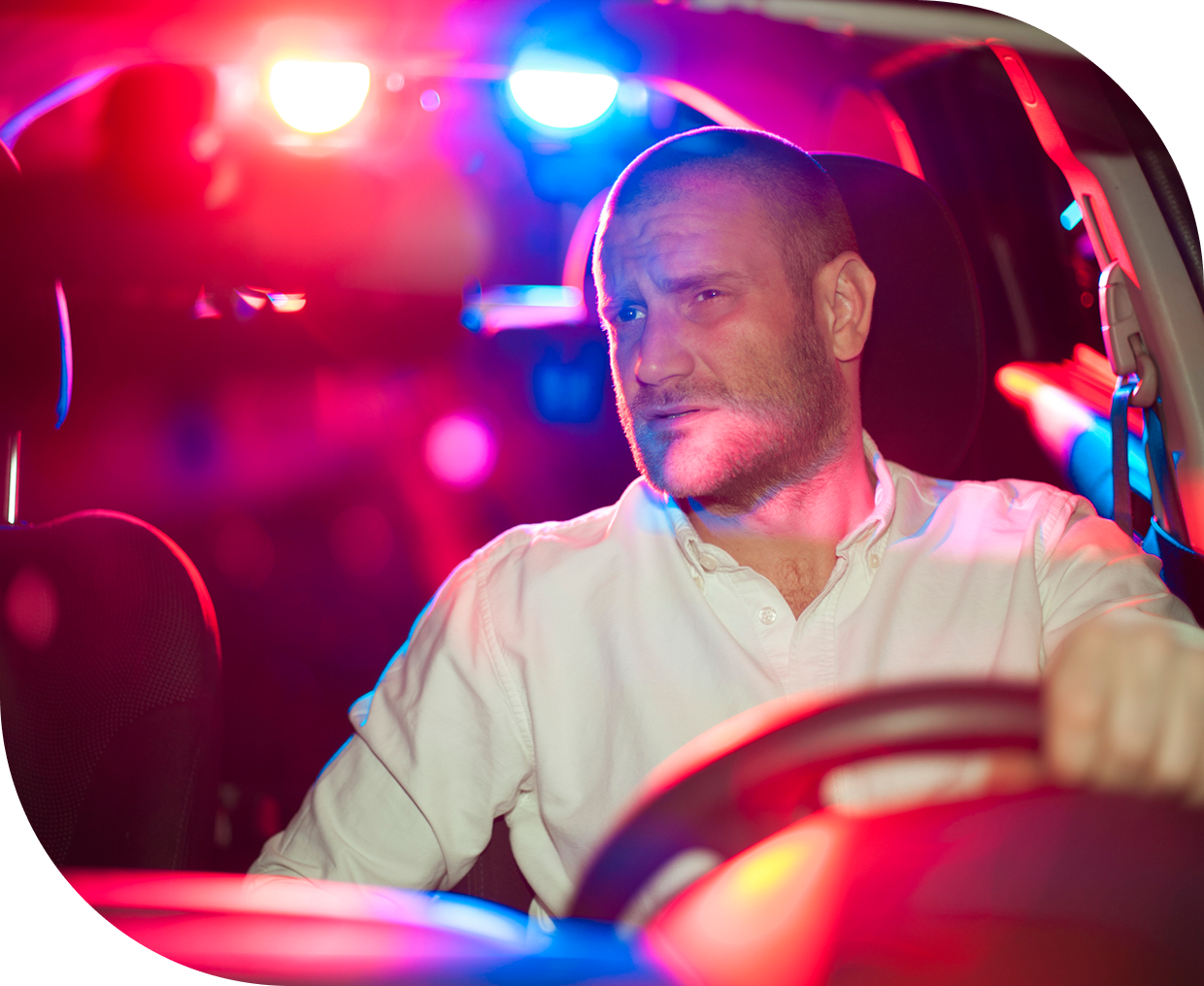 Man driving car with police lights behind.