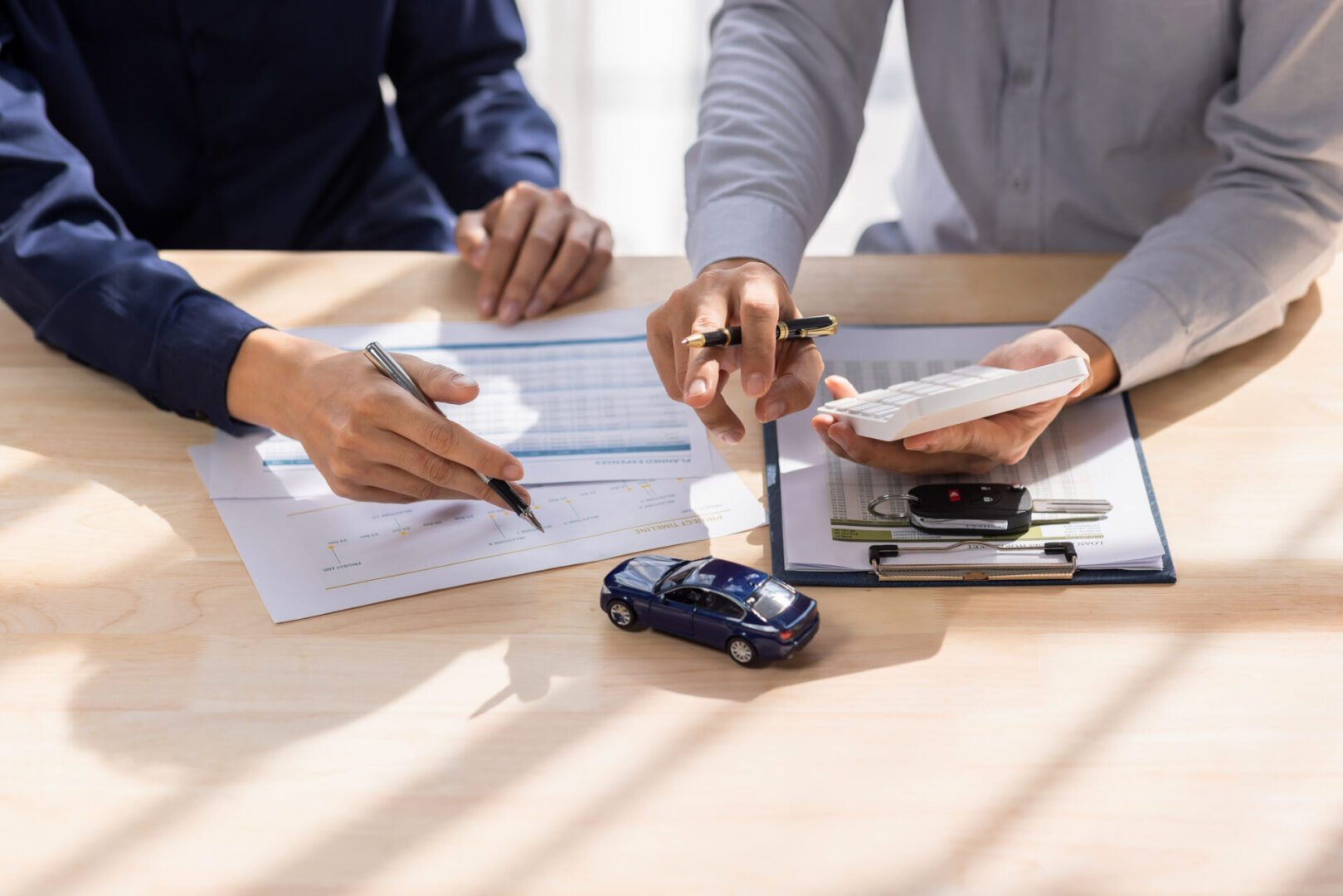 Two people signing car insurance documents.