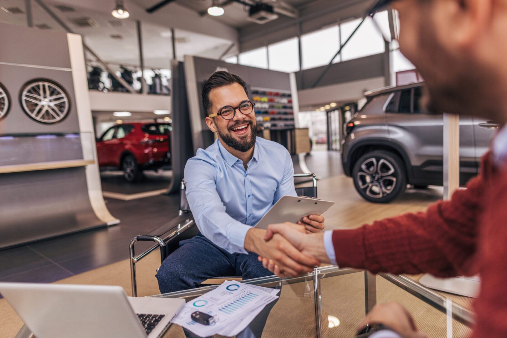 Man shaking hands in car dealership office.