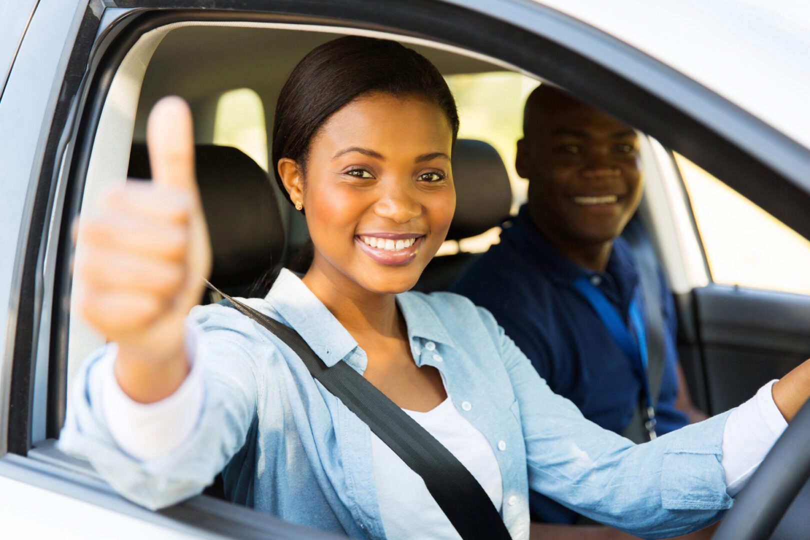 Woman driving car, giving thumbs up.